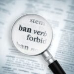A magnifying glass on top of a dictionary page. It is highlighting the word "Ban"