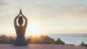 A curly haired girl doing a yoga pose while looking at the sunset representing the focus we will need for 2026