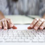An image of a pair of hands about to start typing on a white computer keyboard symbolizing someone about to start writing on a blog.