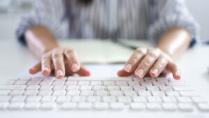 An image of a pair of hands about to start typing on a white computer keyboard symbolizing someone about to start writing on a blog.